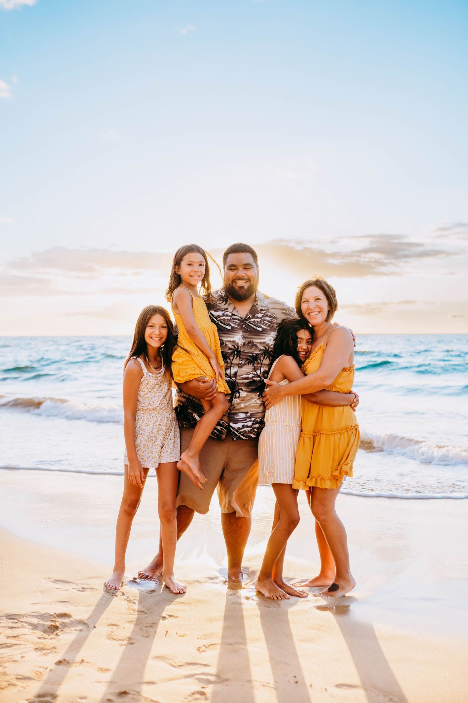 Wailea Family photos on the beach. Family group poses together on beach at sunset wearing coordinated yellow and neutral outfits.