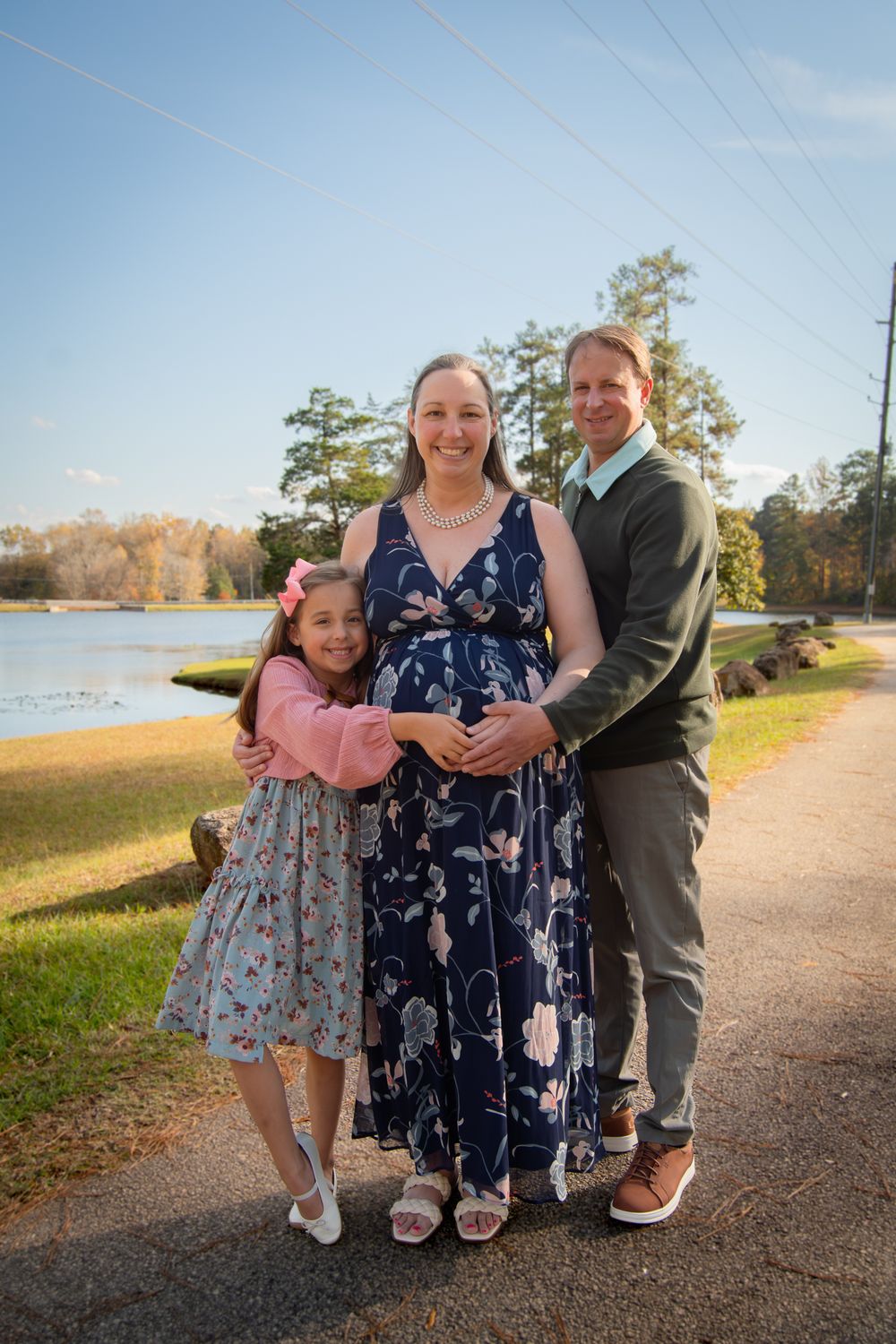 A family poses together on a waterfront path during a golden sunset photo session.