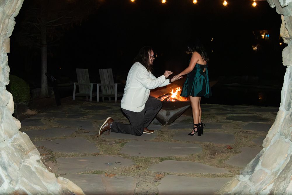 A group of people dance and celebrate at an outdoor nighttime wedding reception with string lights overhead.