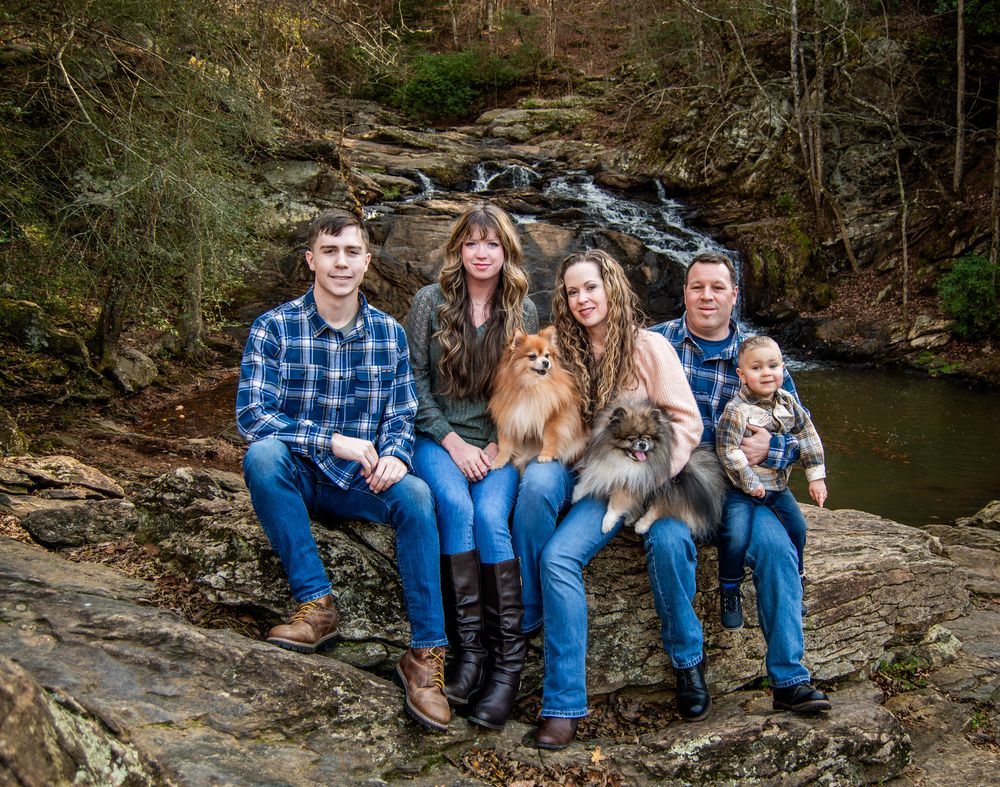Family group sitting together on a rock near a waterfall.
