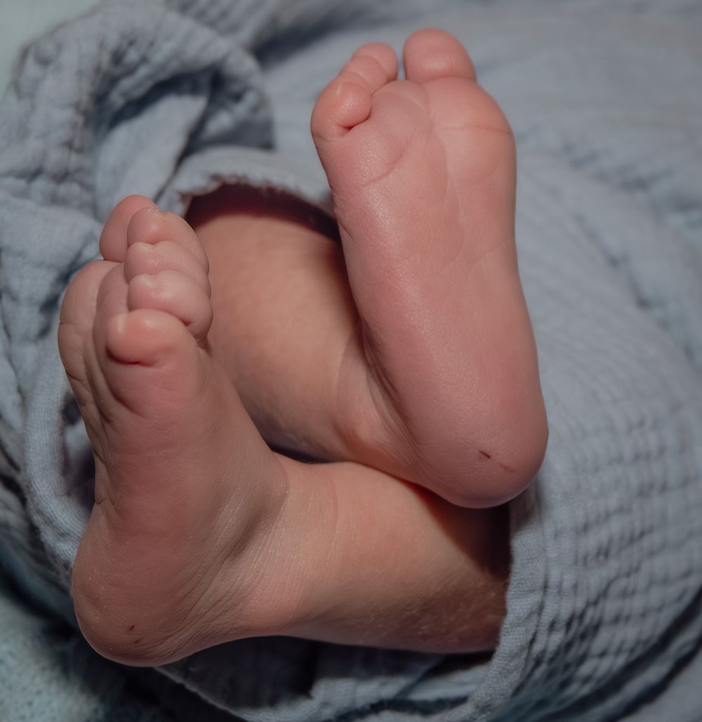 Close-up series of tiny baby feet wrapped in a soft grey blanket.