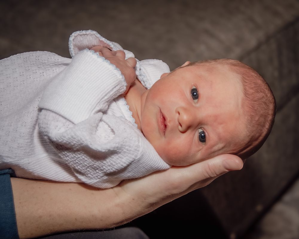 Newborn baby photography series showing an infant in white clothing.