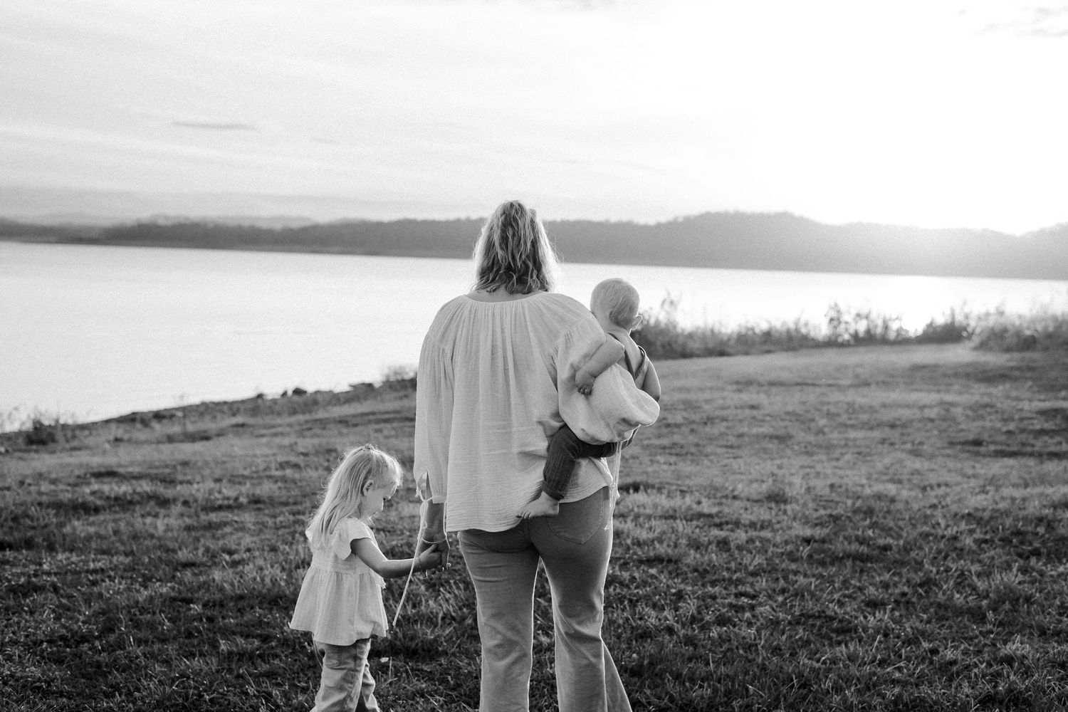 A series of black and white photos showing a family walking together through scenic outdoor landscapes at sunset.