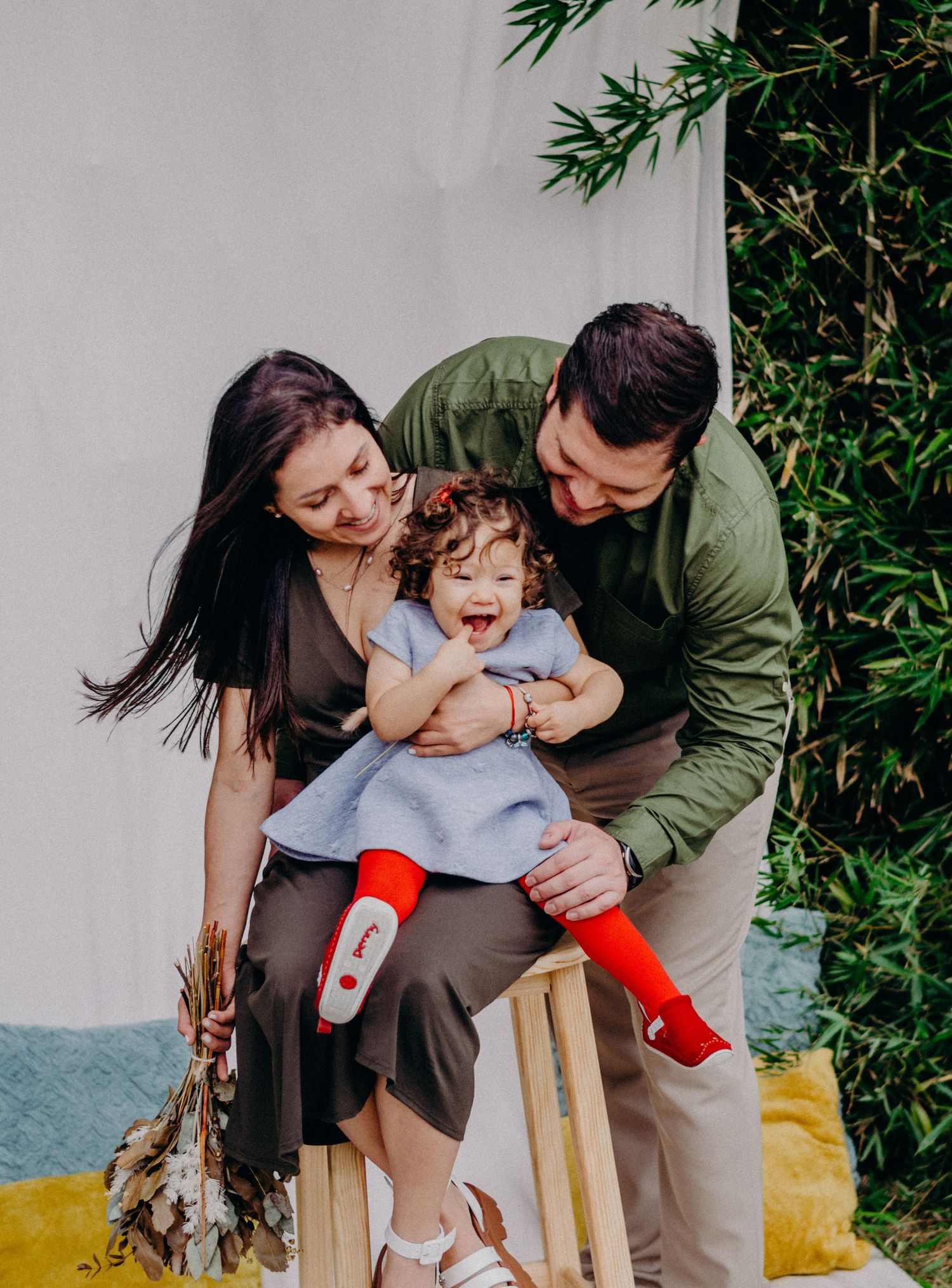 A joyful moment captured of a family playing together near a wall with greenery.
