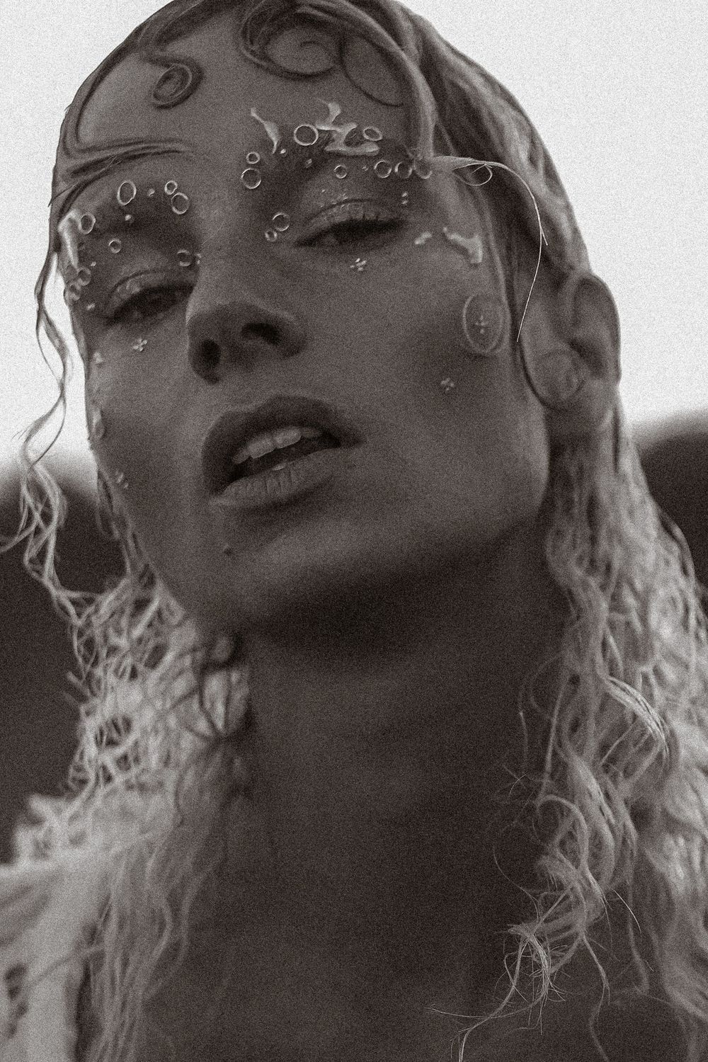 A series of black and white portraits showing a person with curly hair in different expressive poses.