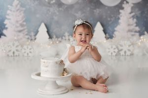 Baby girl with a white and light blue winter wonderland first birthday cake smash set
