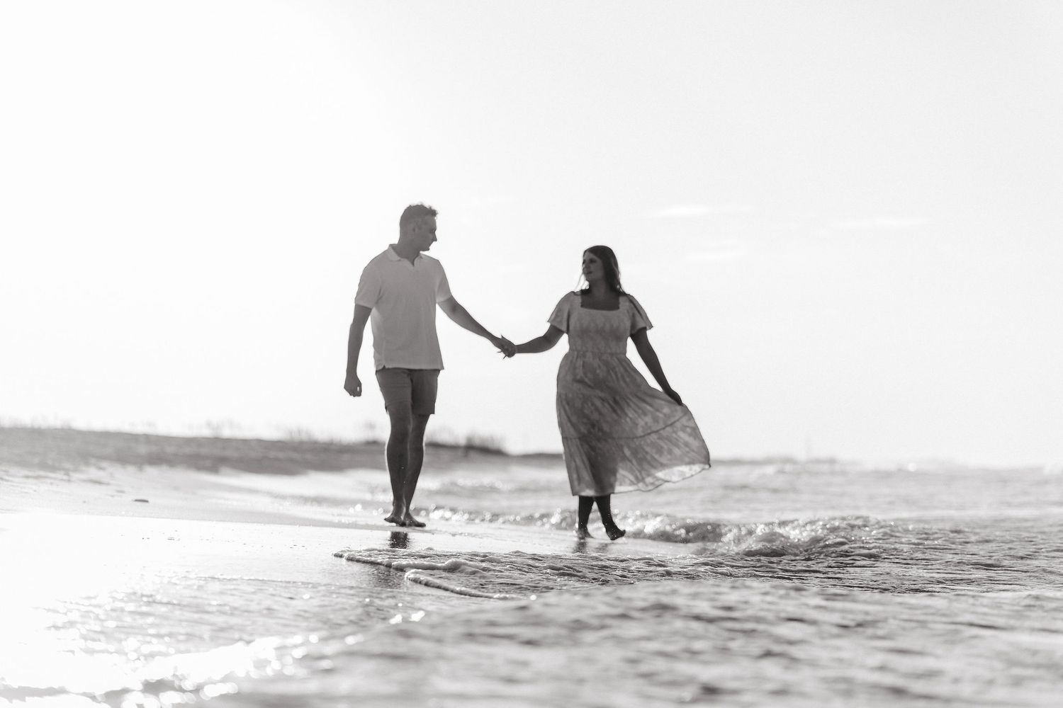 Two silhouettes walk hand in hand on a beach at sunset creating a romantic seaside moment.