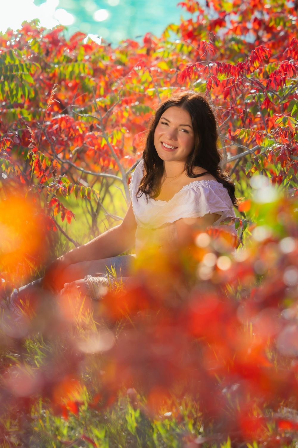 Vibrant red autumn foliage frames a scenic outdoor portrait amidst glowing bokeh effects and natural lighting.