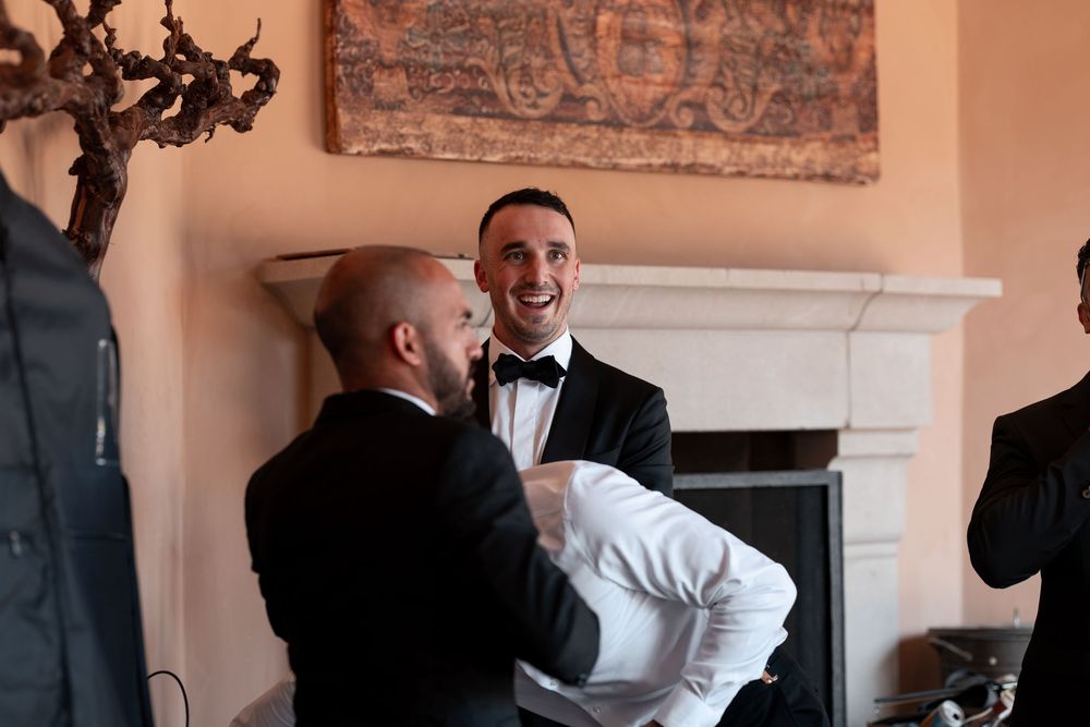 A group of people laugh and smile during a candid moment at an elegant indoor event space.