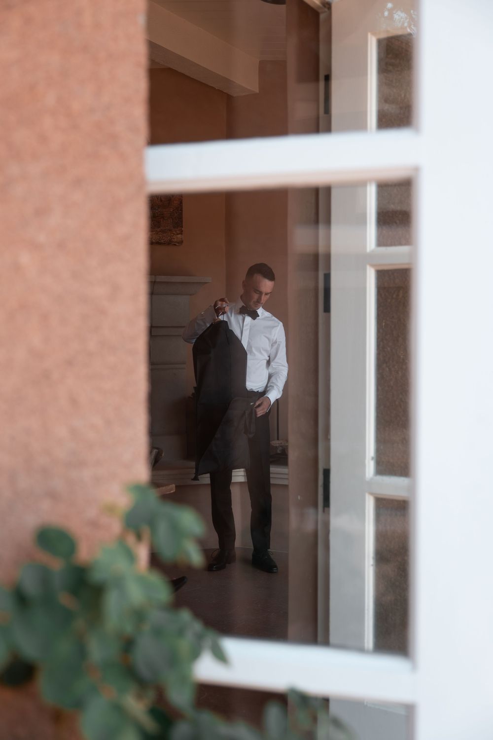 A person in business attire stands near a window in a brick building hallway.