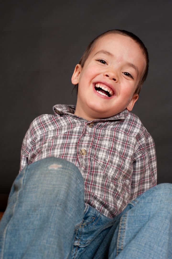 Studio photo of Marshall sitting down while laughing against black paper backdrop.