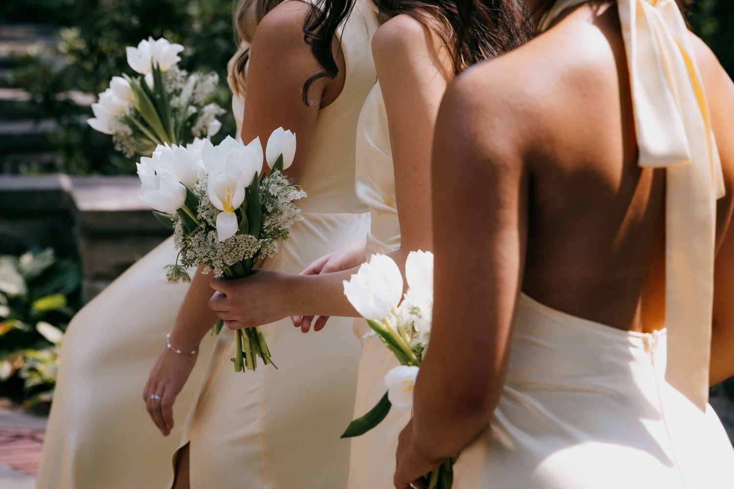 A closeup photo of bridal bouquets as a group of bridesmaids walk past at an outdoor wedding.