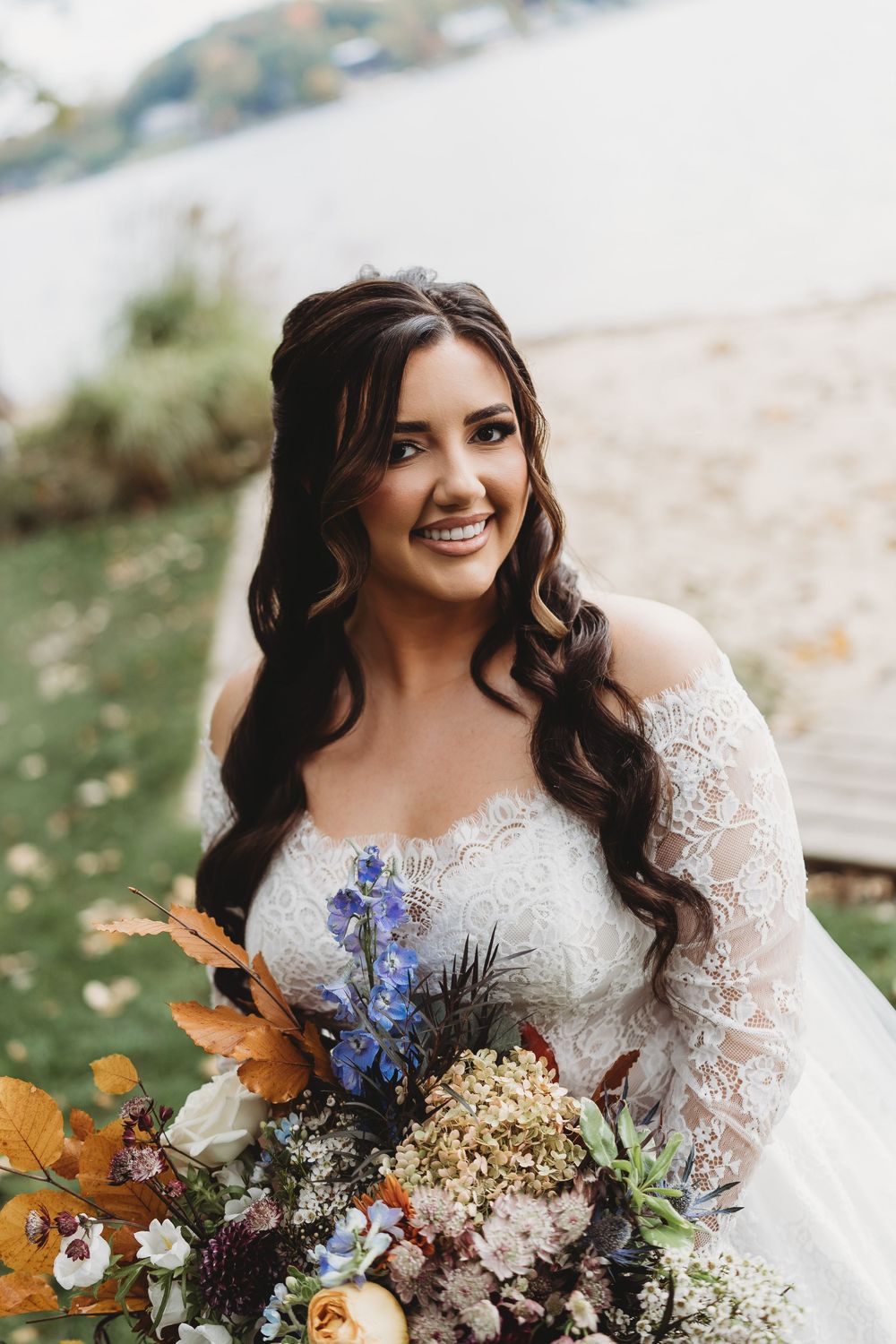 Fall wedding bouquet with orange, blue and white wildflowers against natural outdoor setting.