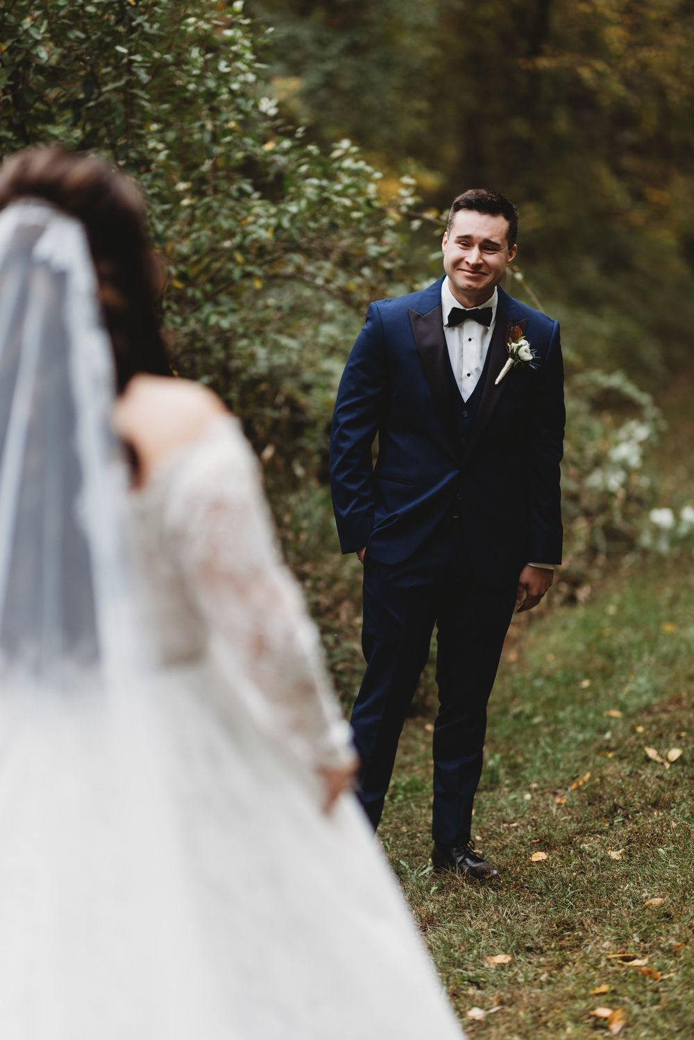 A couple shares a romantic moment during their outdoor fall wedding photoshoot in a wooded setting.
