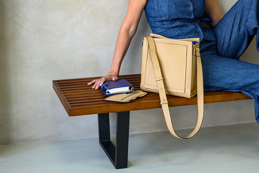 Person sitting on a wooden bench demonstrates how to properly fold and organize laundry with neat stacks.