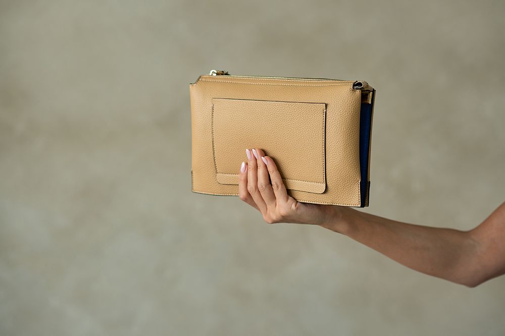 Hand holding a brown cardboard box against a blurred gray background.