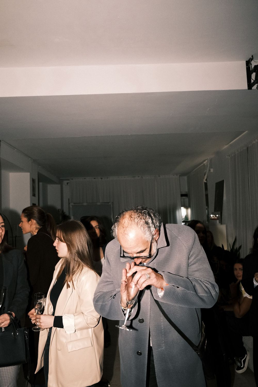 People mingling and socializing at a dimly lit indoor party or event.