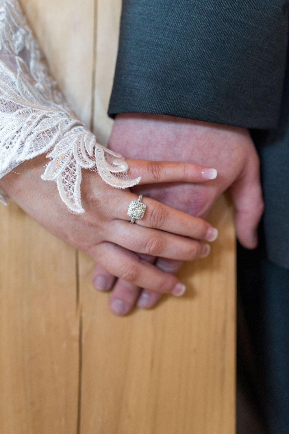 Close-up shot of wedding rings and hands against a wooden background during a ring exchange ceremony.