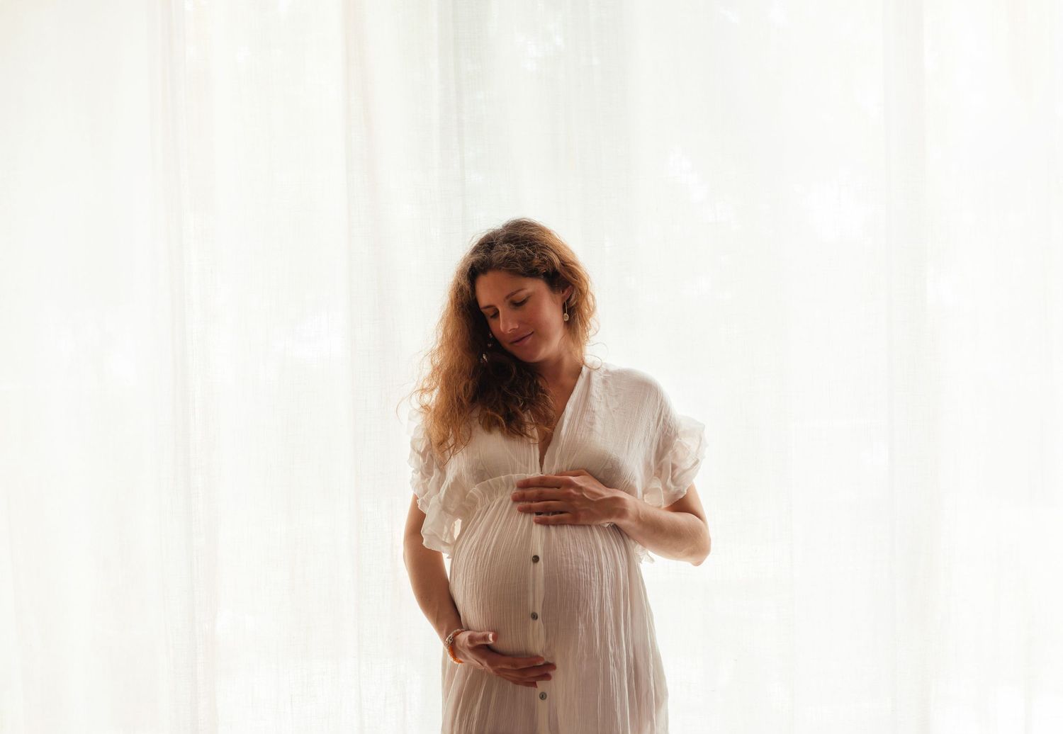 Future maman sublimée dans une robe de maternité dans un décor en studio, séance photo grossesse artistique en lumière naturelle à Niort.