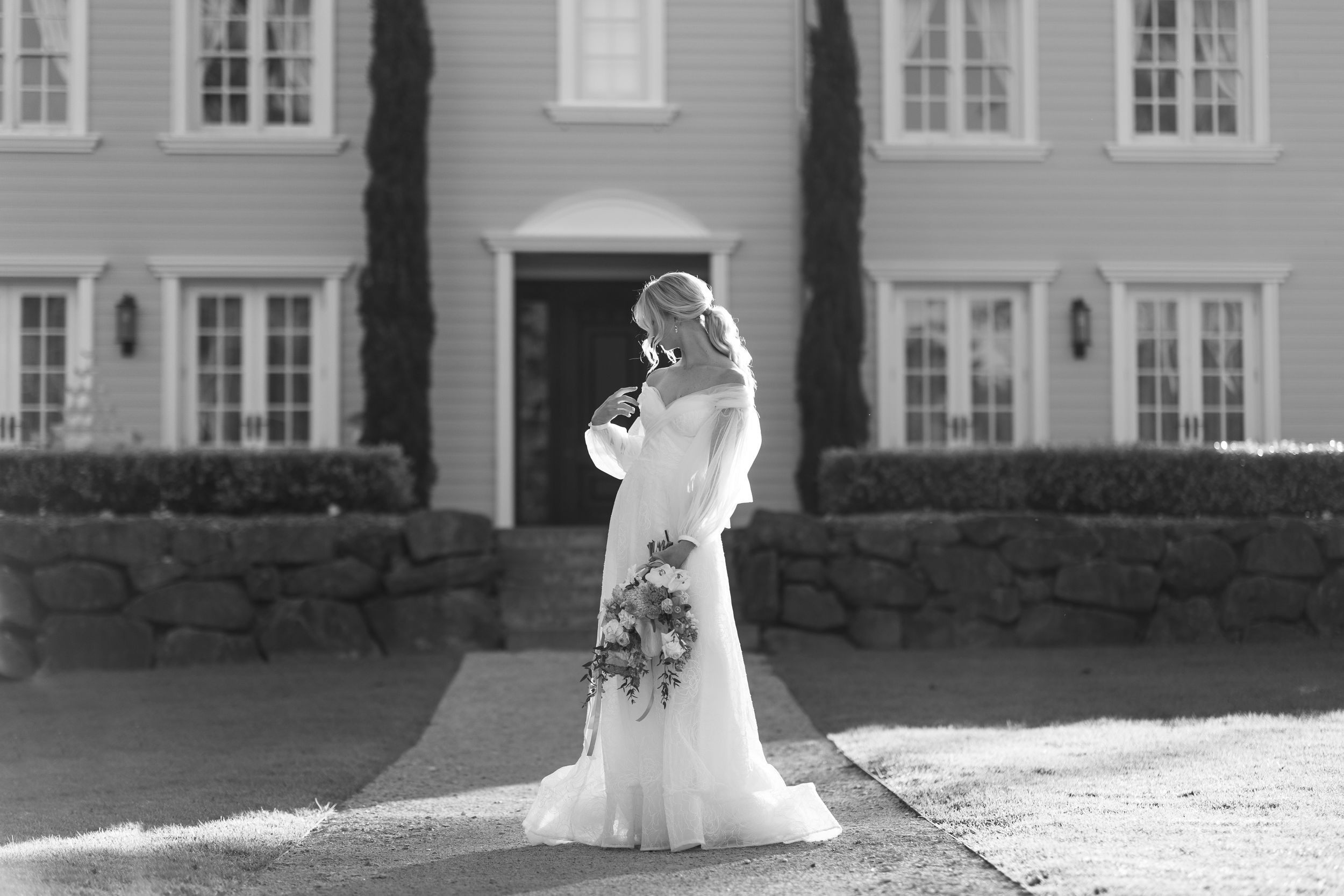 A bride in a flowing white gown stands in front of the  stately mansion at Wynmere at Tamborine Mountain. Scenic Rim