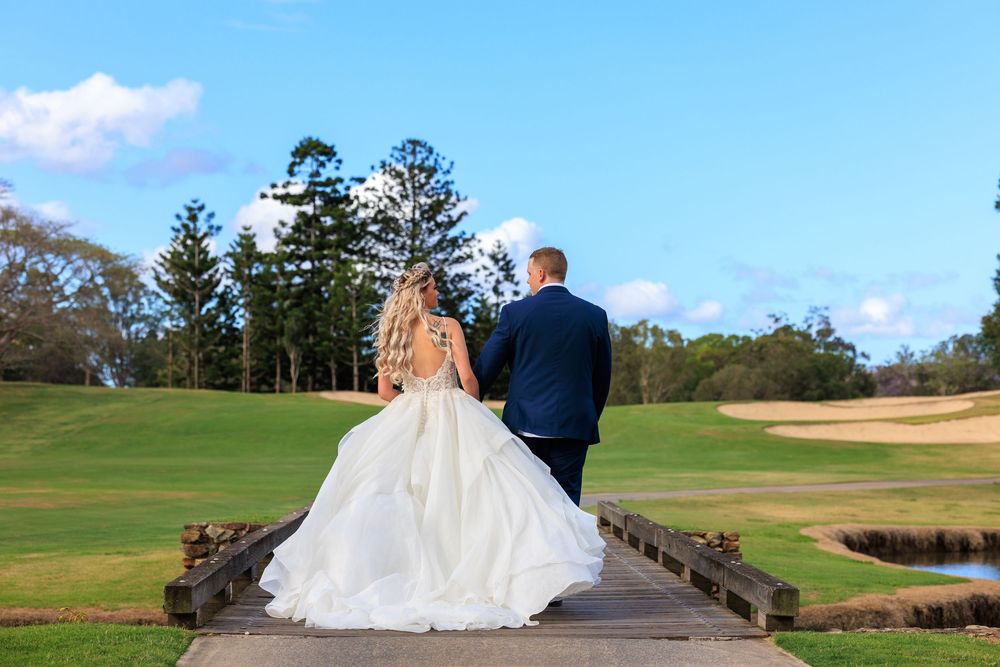 A couple in wedding attire stands on a wooden walkway overlooking  Brisbane golf course.
