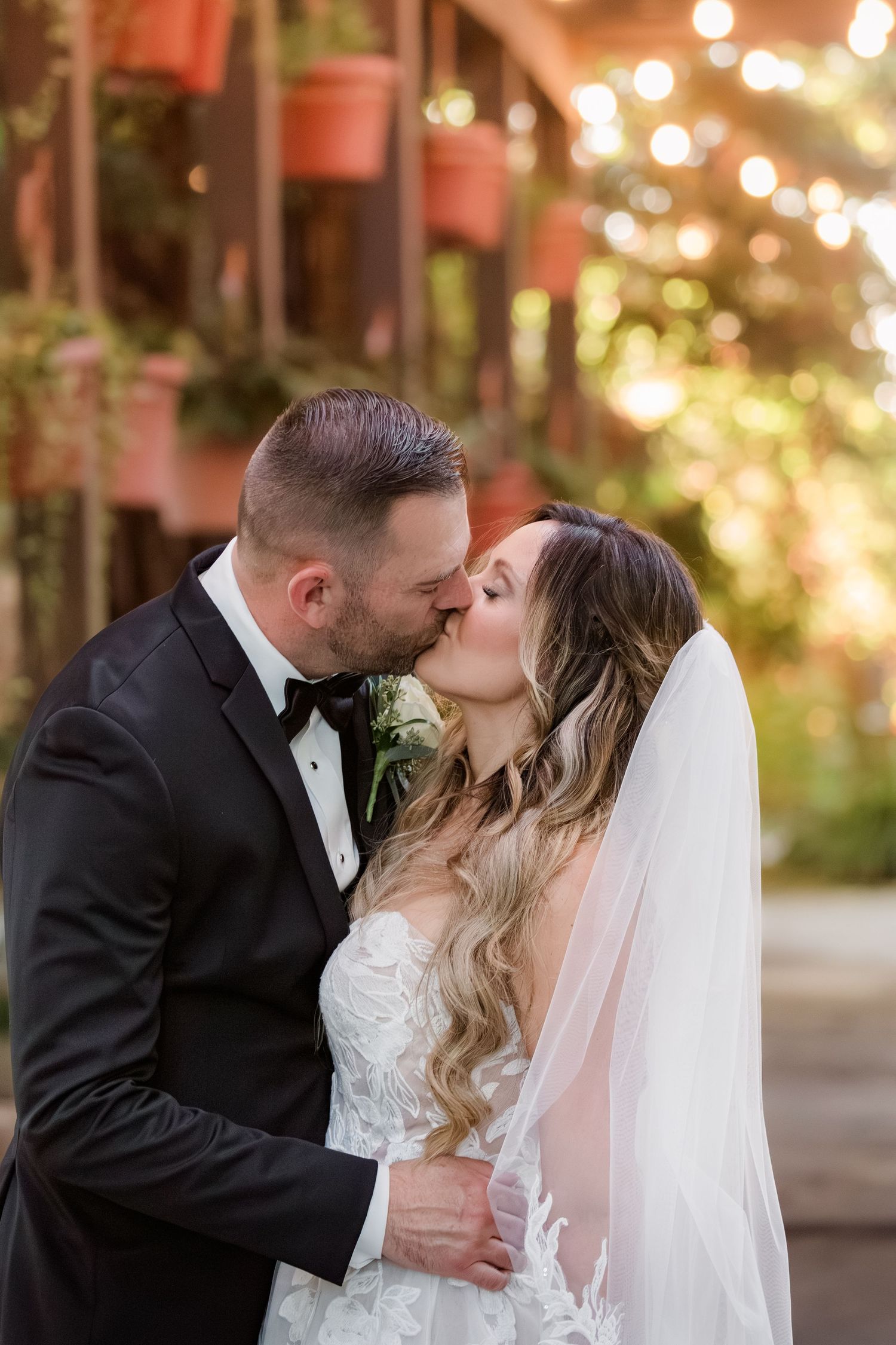 Romantic wedding portraits with string lights creating a warm ambiance in an outdoor setting.