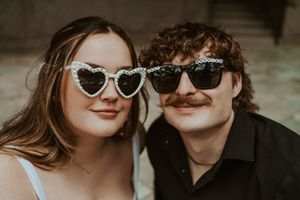 Stylish couple wearing sunglasses posing together outdoors.