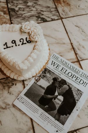 Wedding announcement newspaper clippings and decorative items arranged on marble surface.