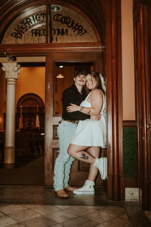 A romantic couple shares an intimate moment in a vintage doorway with ornate architectural details.