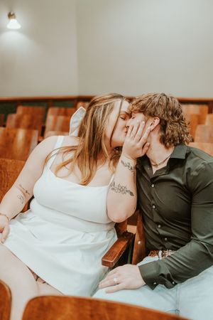 A romantic moment captured in wooden theater seats with warm lighting.