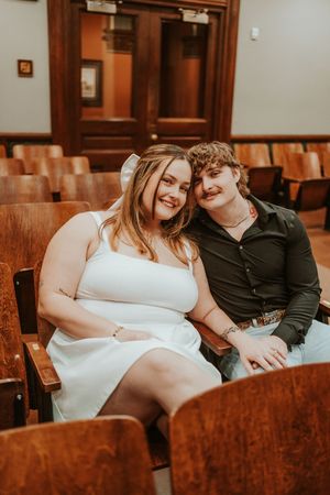 A happy couple sitting together in vintage wooden theater seating.