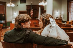 A couple sharing an intimate moment while seated in wooden theater chairs.