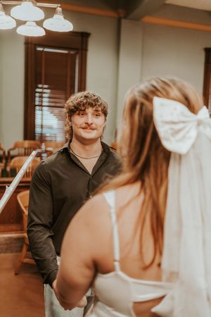 A couple exchanges vows in an elegant room with vintage lighting fixtures.