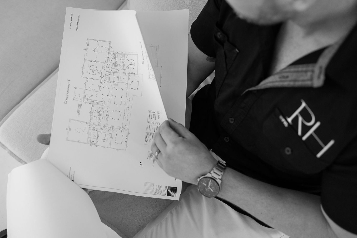 Architectural floor plans and blueprints being reviewed on a white surface.
