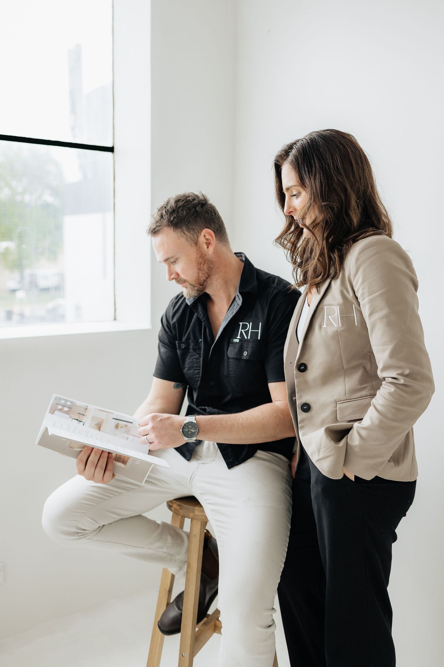 Design professionals examining project materials in modern white office space.