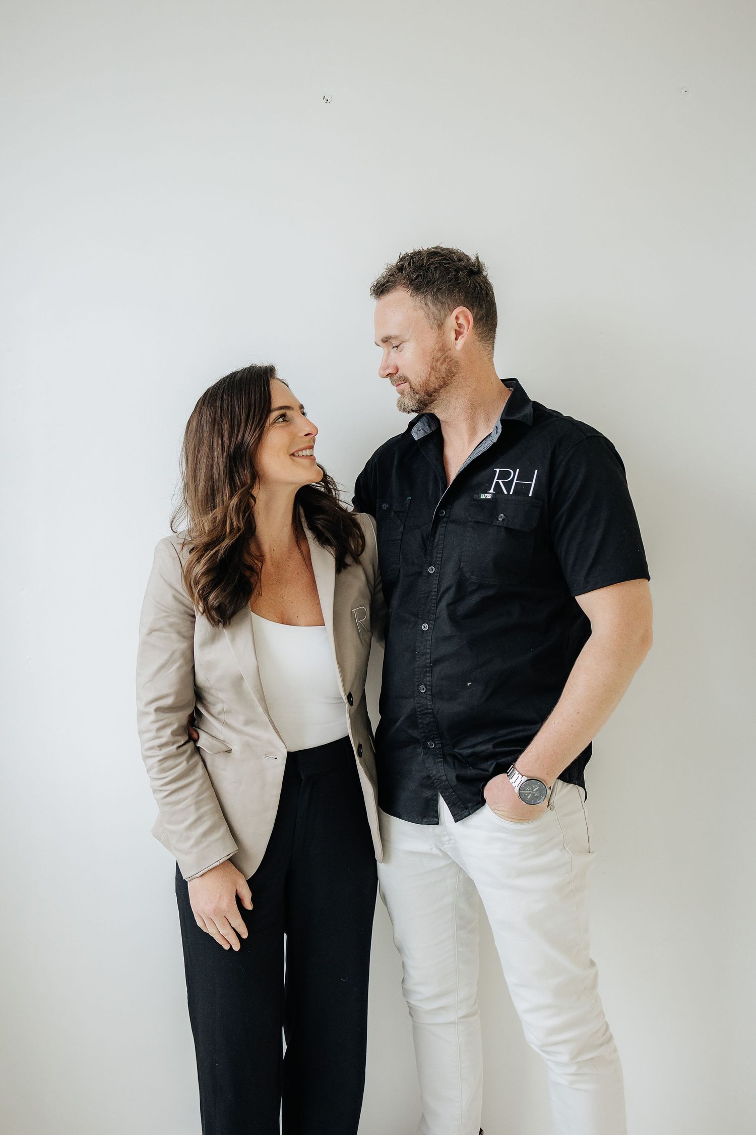 Two people laughing and sharing a candid moment while wearing coordinated black and white business casual outfits.