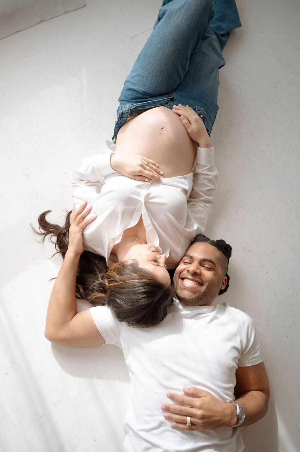 A series of photos showing a pregnant woman in a white shirt lying on the floor with a baby bump.