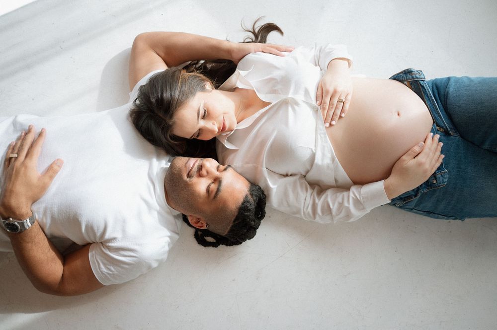 A series of artistic maternity photos showing a pregnant woman in white lying on a light background in different poses.
