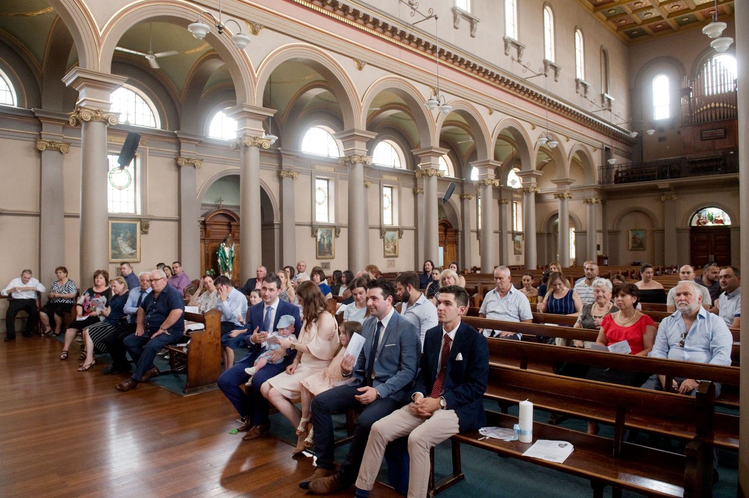 Panoramic view of church interior with wooden pews and ornate architecture.
