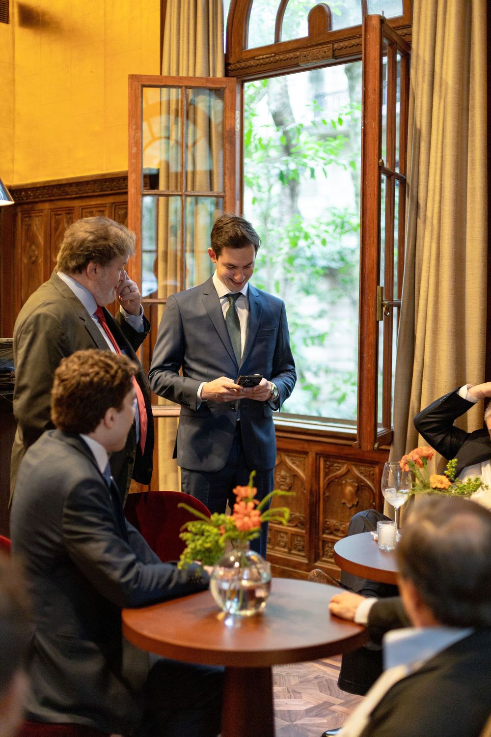 Business professionals gathered around a wooden table in an elegant conference room with natural lighting.