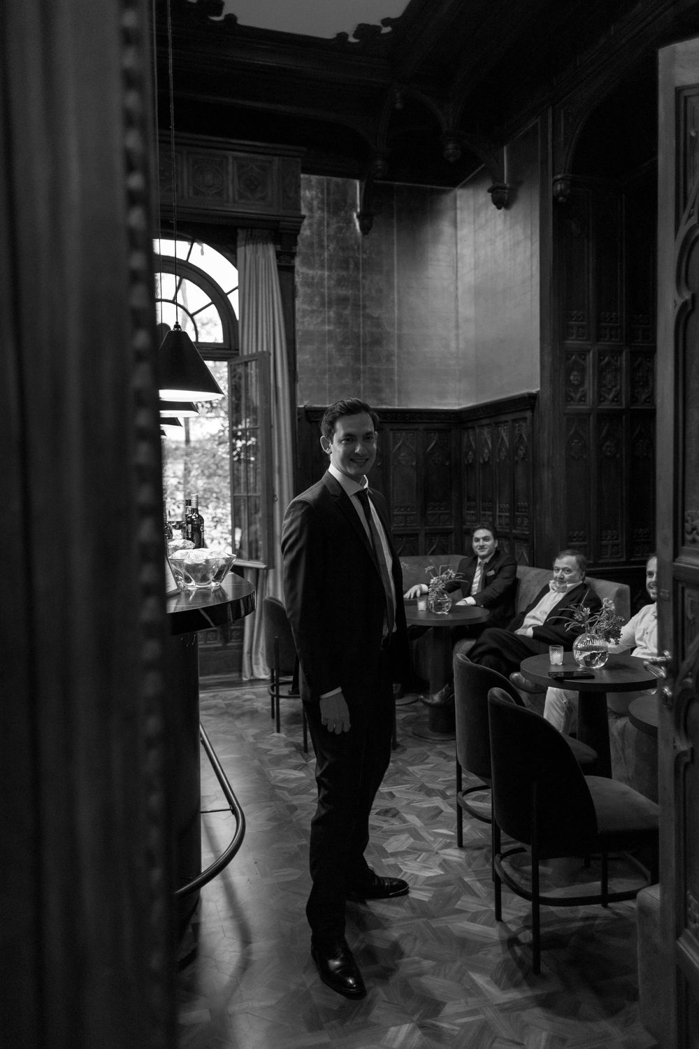 A series of black and white photographs showing people in formal attire conversing in an elegant indoor setting.