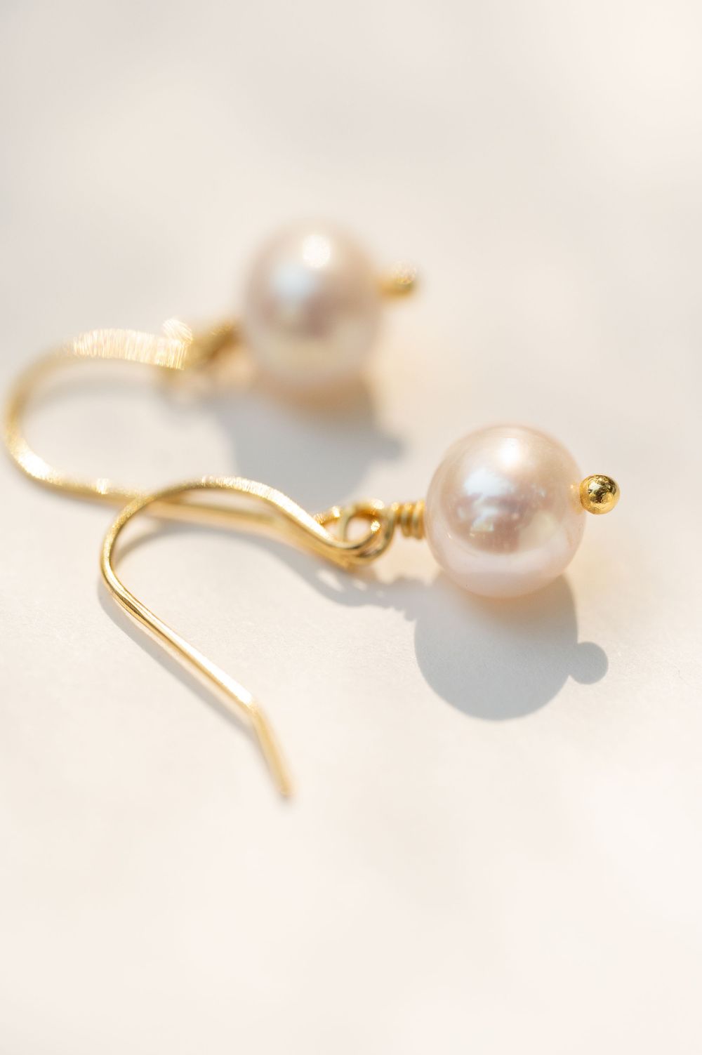 Pearl and gold drop earrings photographed with soft natural lighting.