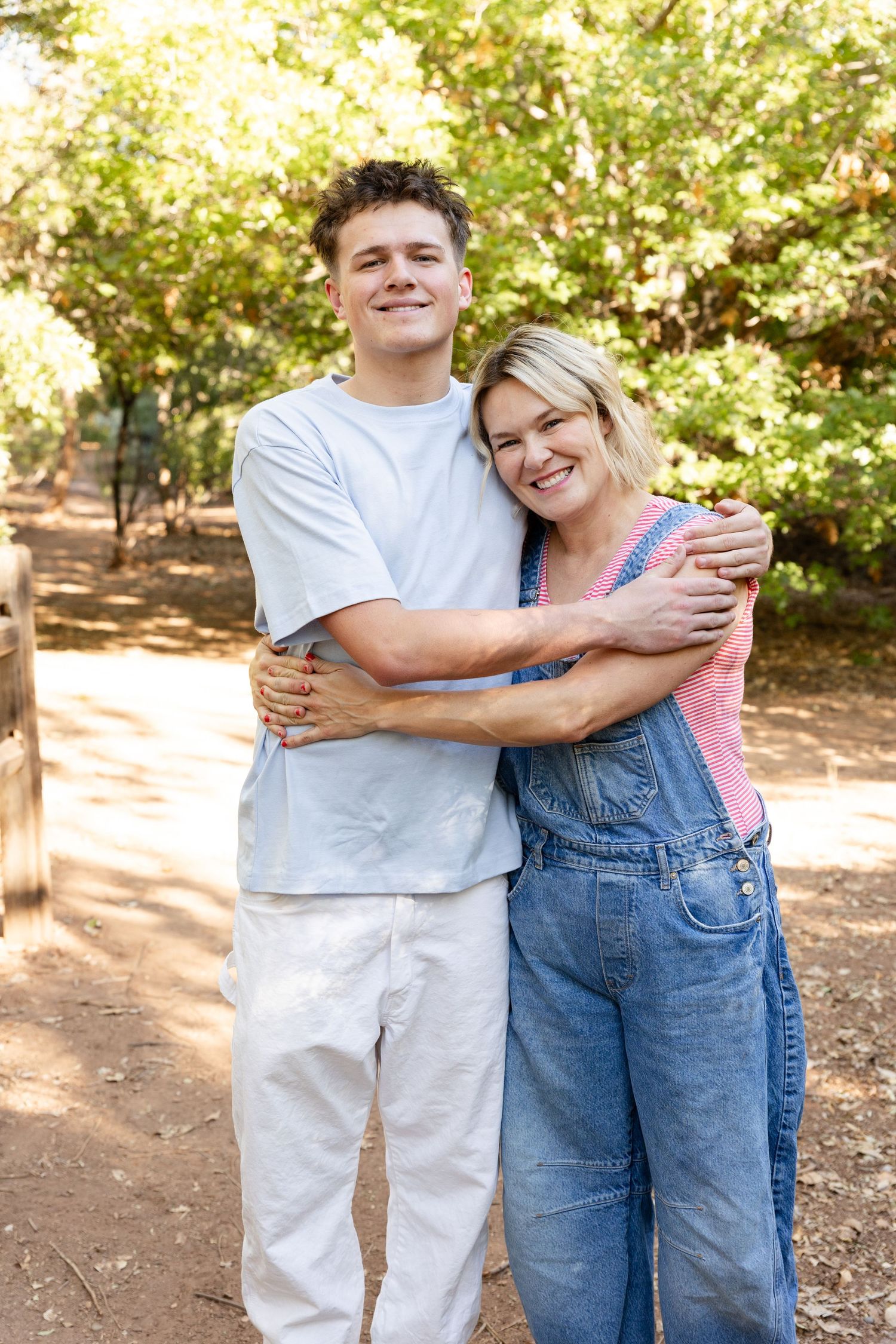 a high school senior boy hugging his mom in a pretty wooded area Tonaquint Park in St. George utah