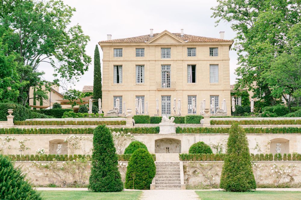 Elegant French chateau with manicured gardens and stone walls showcases classical architecture in warm sunlight.
