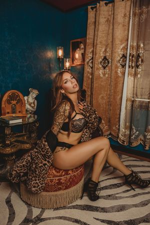 Vintage-style boudoir photoshoot featuring leopard print dress and rustic wooden backdrop with antique decor elements.