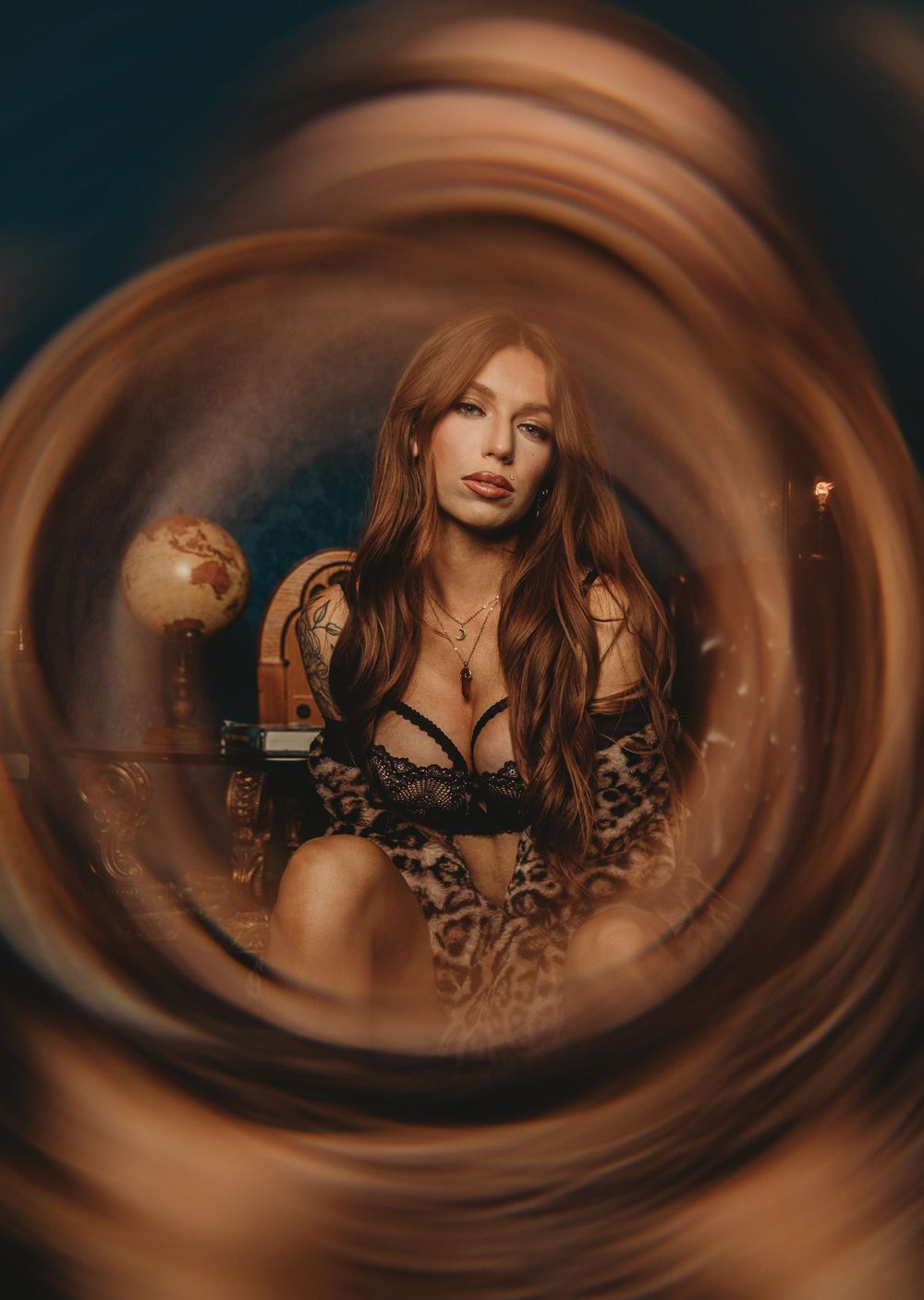 Artistic portrait with swirling brown vignette effect and moody lighting featuring figure in lace against dark background.