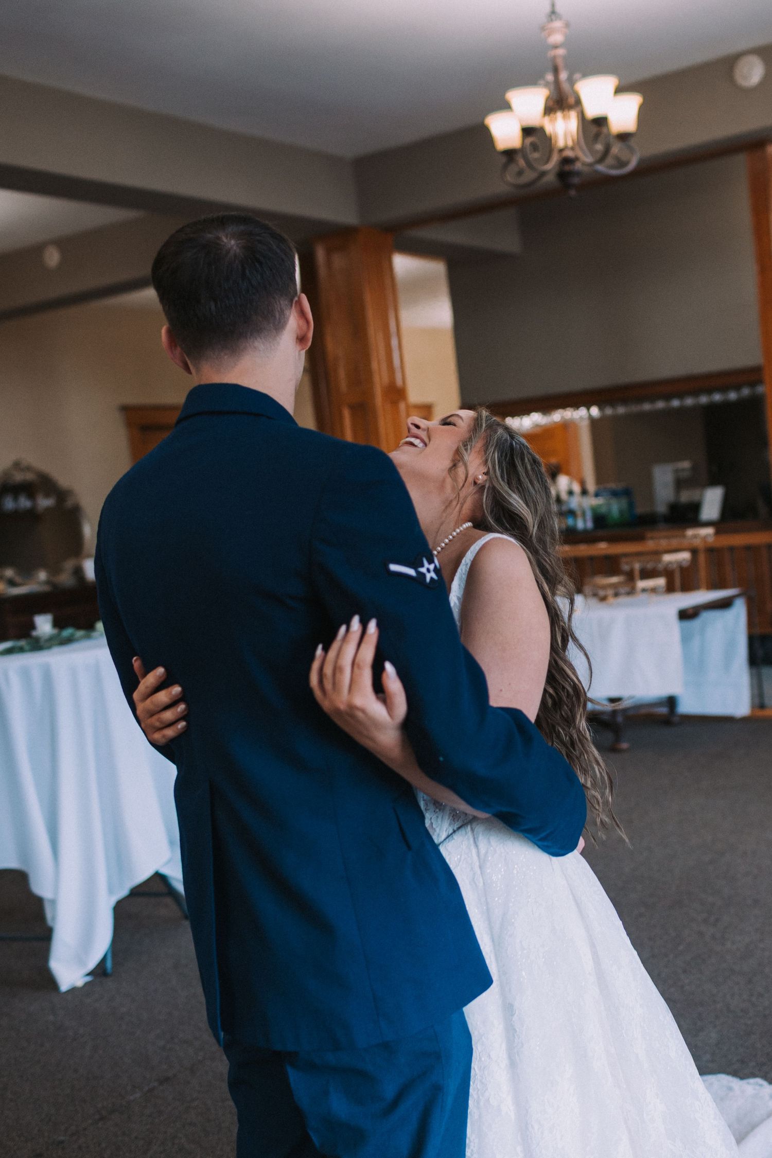 A romantic sequence showing a couple embracing in a room with white linens and chandeliers.