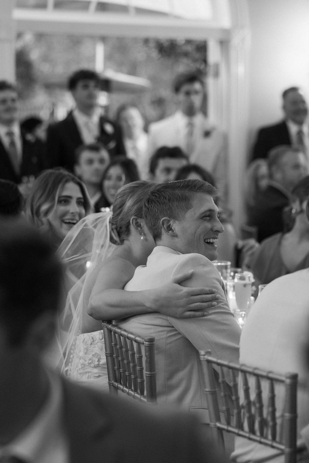 Black and white photo of bride and groom laughing and embracing during a joyful reception moment at Lillian Gardens in Newnan, Georgia