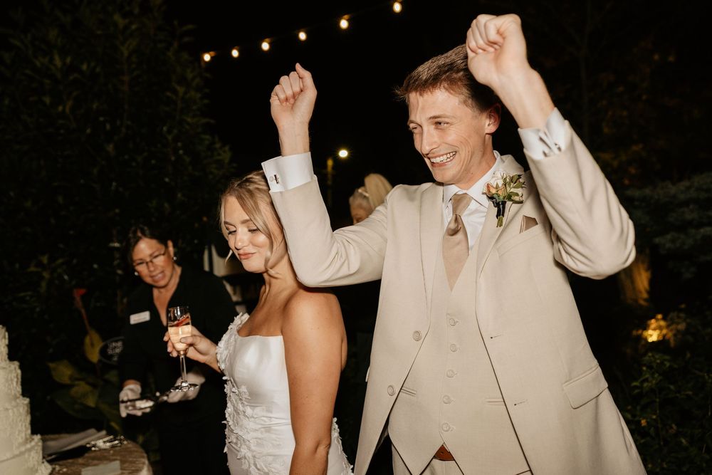Wedding guests dance and celebrate together on a dimly lit dance floor with string lights overhead at Lillian Gardens in Newnan, Georgia