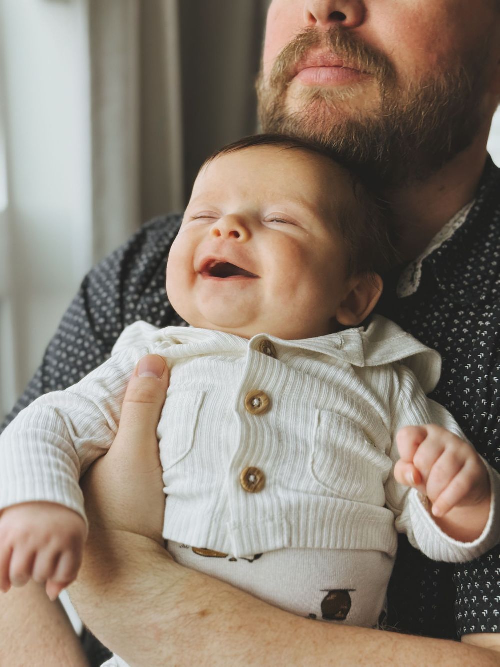 A baby in a white sweater being held by someone wearing a dark polka dot shirt, shown in a series of candid shots.